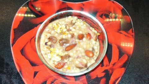 Eine Schüssel Asure, eine türkische süße Suppe, steht auf einem herzförmigen Teller mit roten Rosen.