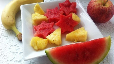 Auf einem Teller sind mit Ausstechformen dekorativ geschnittene Melonenstücke in Sternform, umgeben von Ananas.