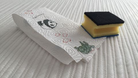 Eine Matratze liegt auf einem Bett, während ein Schwamm zur Reinigung von Erbrochenem bereitsteht.