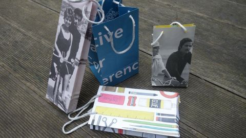 Bunte Geschenktüten aus Zeitschriften stehen auf einer Holzoberfläche, bereit zum Verschenken oder Dekorieren.