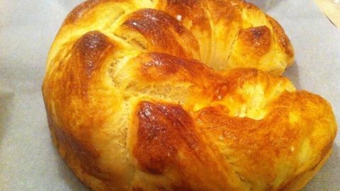 Eine goldbraune, superfluffige Brioche liegt auf einem Backpapier und wartet darauf, serviert zu werden.