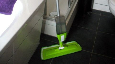 Ein Spraymopp steht in einem Badezimmer, bereit, den Boden effizient zu reinigen. Die Dusche und Badewanne sind sichtbar.
