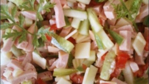 Ein bunter Wurstsalat wird serviert, mit verschiedenen Wurststücken und frischem Gemüse, umgeben von einer ansprechenden Präsentation.