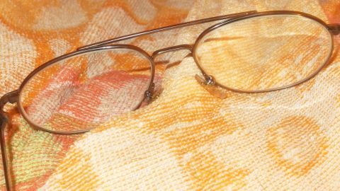 Schlierenfreien Durchblick, mit einer Mischung aus einem Teil Wasser und zwei Teilen Spiritus, funktioniert besser als Spülmittel, in denen oft Handpflegemittel sind, die Schlieren bilden. Eine Brille liegt auf einem gemusterten Tuch, bereit, mit Wasser und Spiritus gereinigt zu werden.