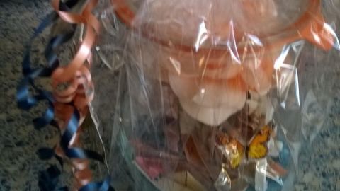 Ein dekorativ verpacktes Geldgeschenk in einer transparenten Folie mit bunten Schleifen auf einer Küchentheke.