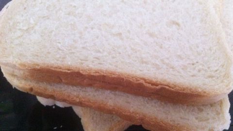Zwei Scheiben frisches Toastbrot liegen übereinander auf einem Teller und zeigen eine goldene, leicht knusprige Oberfläche.