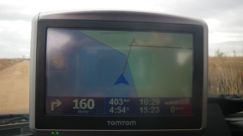 Ein Navigationsgerät zeigt eine Route an, während das Auto auf einer ländlichen Straße in Spanien fährt.