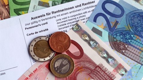Ein Rentnerausweis liegt auf Geldscheinen und Münzen, symbolisiert finanzielle Vorteile für Senioren im Alltag.