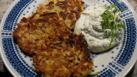 Kohlrabi-Kartoffel-Rösti liegt knusprig auf einem Teller, begleitet von cremigem Kräuterquark und frischer Spitze.