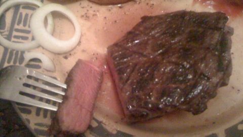 Ein saftiges Steak, perfekt gebraten, liegt auf einem Teller neben goldbraunem Gemüse und einer Gabel.