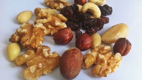 Eine abwechslungsreiche Mischung aus Nüssen und Trockenfrüchten liegt auf einem weißen Teller, ideal für mehr Power fürs Gehirn.