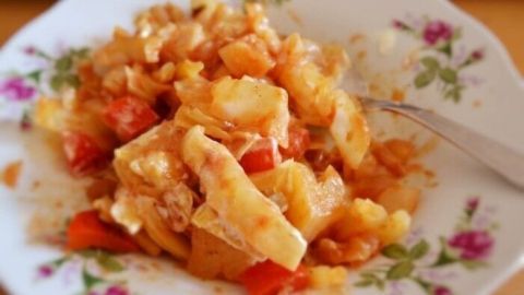 Ein Teller mit Tomatenkraut zeigt eine bunte Mischung aus Gemüse, die appetitlich angerichtet ist, umgeben von floralen Mustern.