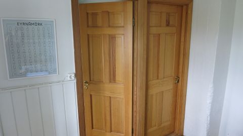 Zweiflügelige Zimmertüren öffnen sich harmonisch in einem hellen Raum mit einem sanften Holzfußboden und einer Wandtafel.