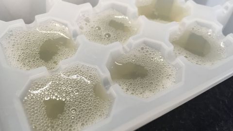 Einfrierwürfel mit frischem Zitronensaft, der in kleinen Portionen gefüllt ist und dabei Blasen bildet.