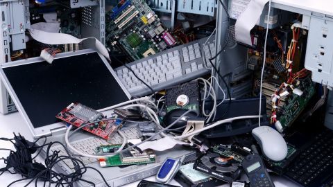 Ein Haufen alter Elektrogeräte, wie Computerteile und Handys, liegt chaotisch verteilt auf einem Tisch und verdeutlicht die Notwendigkeit zur richtigen Entsorgung.