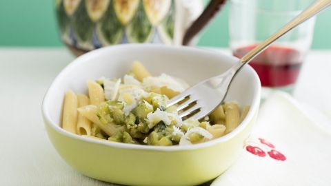 Zucchininudeln in einer bunten Schüssel, garniert mit Käse und einem Gabel in einem hellen, freundlichen Raum.