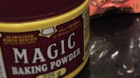 Eine Verpackung mit Backpulver steht auf einer Arbeitsfläche, umgeben von ähnlichen Produkten, um das Backen zu erleichtern.
