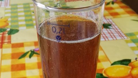 Ein Glas Longdrink steht auf einem bunten Tisch mit karierten und gemusterten Tischtüchern.