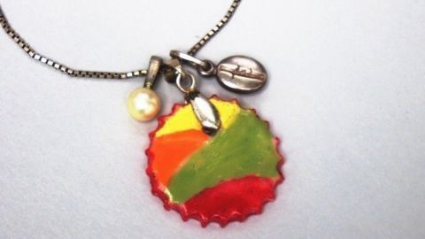 Ein bunter Kettenanhänger aus Fimo hängt an einer Silberkette und zeigt eine kreative Mischung aus Farben und Anhängern.