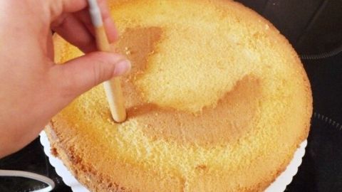 Eine Hand hält einen Spatel, der sanft einen trockenen Kuchen bearbeitet, um ihn aufzupeppen und zu retten.