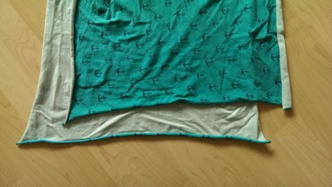 Ein farbiger Jersey liegt quer auf einem hellen Untergrund, wobei die rechte Seite sichtbar und in Verwendung ist.