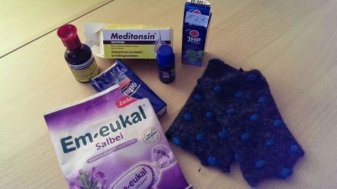 Auf dem Tisch liegen verschiedene Produkte zur Linderung von Infekten, darunter Hustenbonbons und Medikamente.