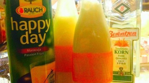Eine Flasche Maracuja Schnaps steht neben einer Tetra-Packung Fruchtsaft, umgeben von warmer Küchendekoration.