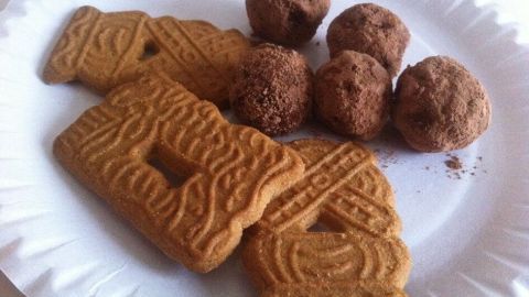 Die feinen Spekulatius-Trüffel liegen neben knusprigen Spekulatiusplätzchen auf einem weißen Pappteller.