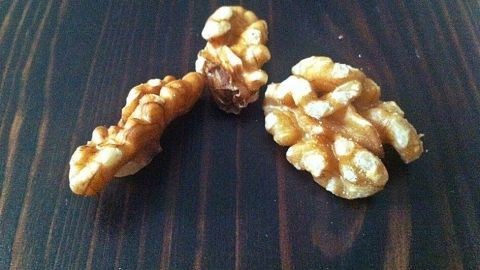 Auf der dunklen Holzoberfläche liegen mehrere Walnüsse, die darauf warten, bearbeitet oder verarbeitet zu werden.