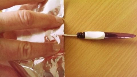 Ein Fadentrenner schneidet durch Folie, w&auml;hrend eine Hand stabilisierend darauf dr&uuml;ckt, um pr&auml;zise Arbeiten zu erm&ouml;glichen.