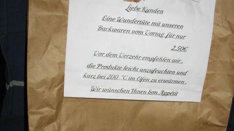 Eine braune Papiertüte steht auf einem Stuhl, beschriftet mit Informationen über Brot und Brötchen aus der Wundertüte.