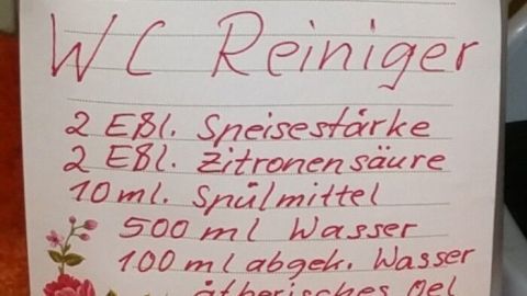 Eine Flasche mit selbstgemachtem WC-Reiniger steht auf einer Oberfläche, beschriftet mit Inhaltsstoffen und Anweisungen.