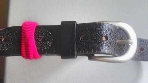Ein Gürtel mit fehlender Gürtelschlaufe wird improvisiert, indem ein pinker Gummi als Ersatz verwendet wird.
