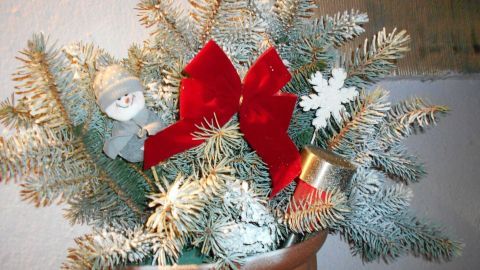 Weihnachtlich gestaltete Blumenkästen sind mit grünen Tannenzweigen, roten Bändern und einer kleinen Figur dekoriert.