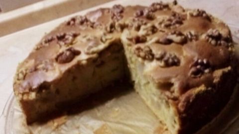 Ein Apfelkuchen mit einem Stück herausgeschnitten steht auf einem Teller, umgeben von einer hellen Küchenarbeitsplatte.