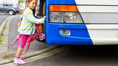 Ein Kind mit Rucksack steigt sicher in den Schulbus, um richtiges Verhalten bei Busfahrten zu zeigen.