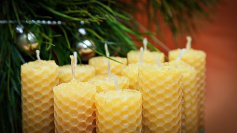 Wachskerzen stehen in einer Gruppe, umgeben von grünem Tannenzweigen und silbernen Christbaumkugeln, ideal für Weihnachtsdeko.