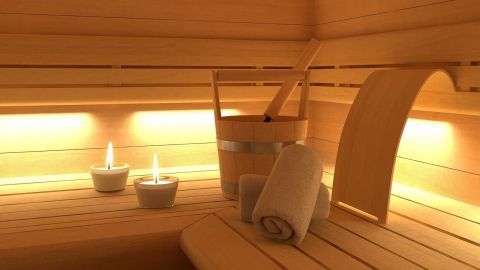 Ein Holzsauna-Inneres zeigt Bänke, einen Eimer und zwei Teelichter, ideal für entspannendes Saunieren.
