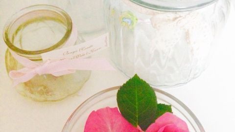 Zwei pinkfarbene Rosen liegen in einer Glasschüssel, umgeben von klaren Glasgefäßen auf einem hellen Tisch.
