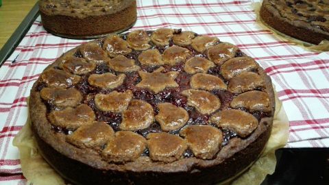 Eine Linzertorte aus mehreren Schichten mit himmlischer Füllung liegt auf einem karierten Geschirrtuch in einer warmen Küche.