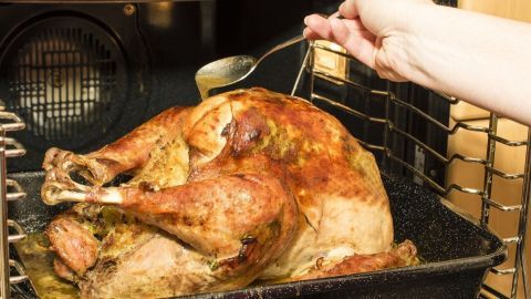 Eine goldbraune Gans wird im Ofen mit einer Soße übergossen, um sie nicht zu trocken zu machen.