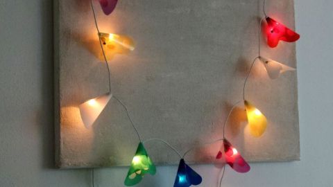 Bunte Lichterkette mit selbst gebastelten Schirmchen schmückt die Wand und leuchtet in verschiedenen Farben.