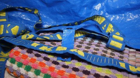 Eine robuste IKEA-Tasche liegt auf einem bunten Handtuch, bereit für den Schwimmhallenbesuch, um Utensilien zu transportieren.
