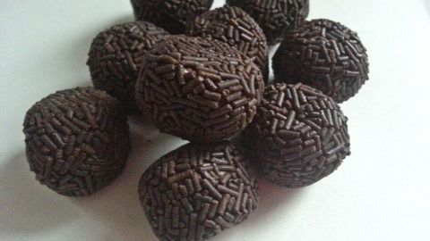 Kugelförmige Rumkugeln liegen zusammen auf einer weißen Fläche, überzogen mit Schokoladestreuseln, bereit zum Naschen.