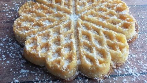 Norwegische Waffeln liegen auf einem Holztisch, frisch gebacken und mit Puderzucker bestreut, bereit zum Genießen.