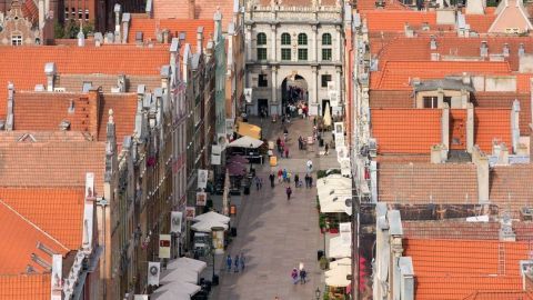 Eine malerische Straßenansicht in Polen, in der Menschen lebhaft einkaufen und die bunten Gebäude umgeben.