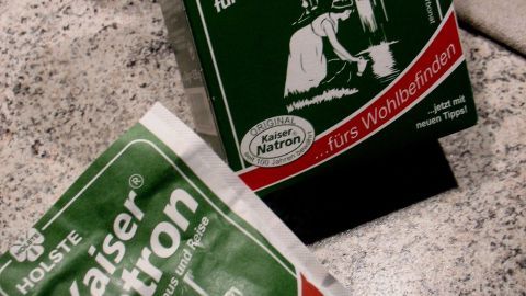 Zwei Verpackungen von Kaiser Natron liegen auf einer Arbeitsplatte, umgeben von einem leicht verschwommenen Hintergrund.