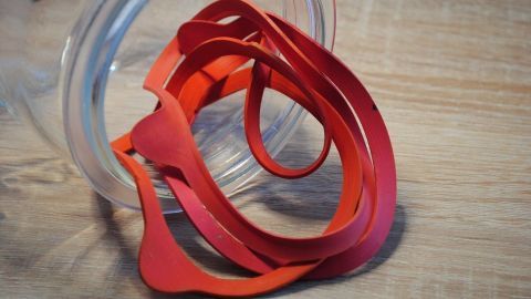 Rote Gummibänder liegen locker in einem durchsichtigen Behälter, bereit zum Einkochen im Backofen zu verwenden.