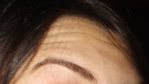 Ein gut gepflegtes Augenbrauen-Design ist sichtbar, während eine Mascara-Bürste darauf angewendet wird, um Form zu schaffen.