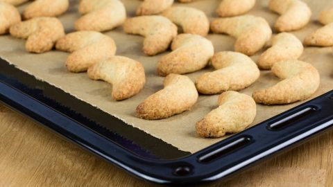 Auf einem Backblech liegen frisch gebackene Vanillekipferl, die goldbraun und lecker aussehen.